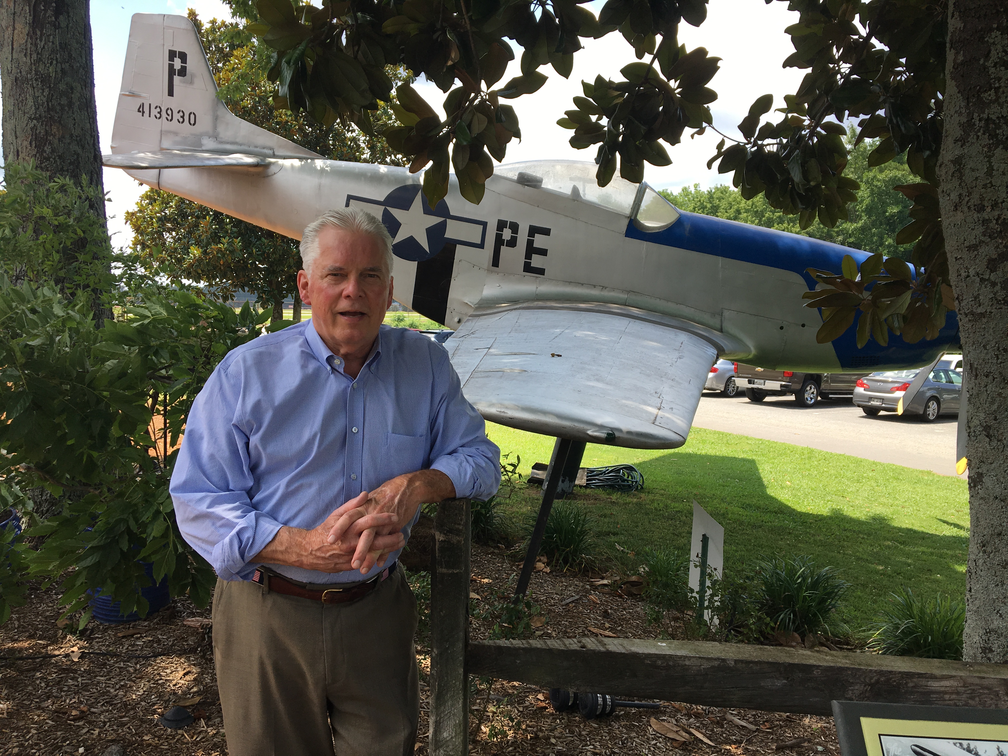 Steve Sasser standing in front of a vintage propeller plane mounted on a pole
