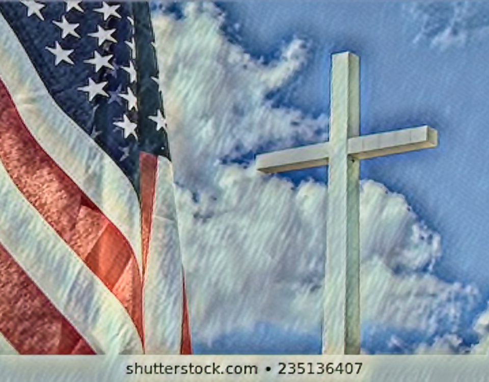 An American flag beside a white cross against a cloudy blue sky