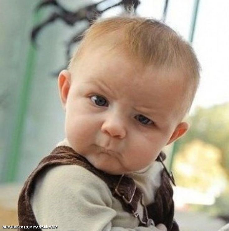 A baby frowning at the camera with one eyebrow raised