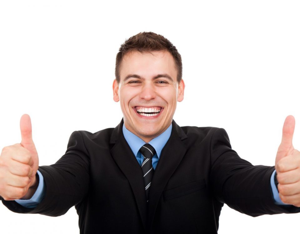A smiling man in a suit giving two thumbs up